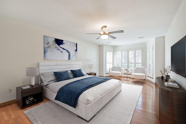 bedroom with a ceiling fan, baseboards, visible vents, and wood finished floors