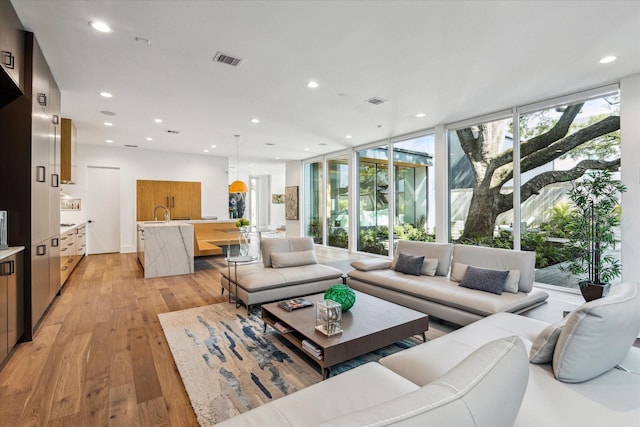 living area featuring floor to ceiling windows, light wood finished floors, visible vents, and recessed lighting