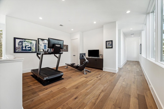 exercise area with baseboards, recessed lighting, light wood-style flooring, and a healthy amount of sunlight