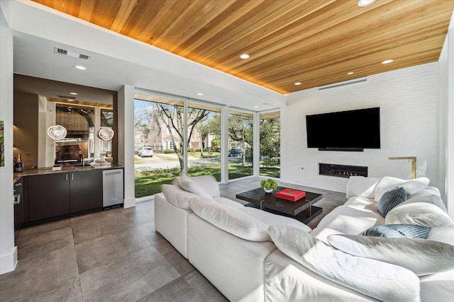 living area with visible vents, a glass covered fireplace, wood ceiling, a tray ceiling, and recessed lighting