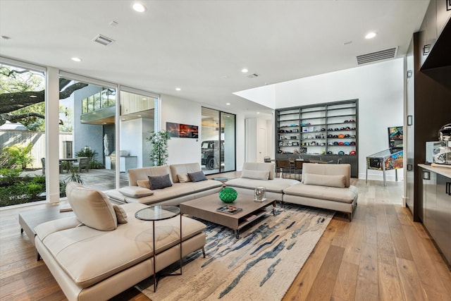 living room with a wall of windows, recessed lighting, visible vents, and light wood finished floors