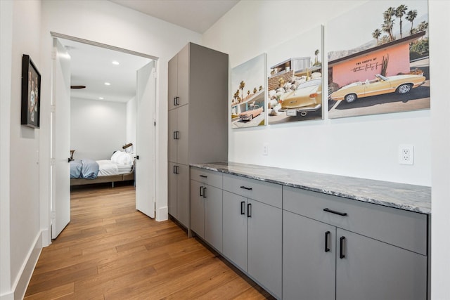 corridor with light wood-style flooring, baseboards, and recessed lighting