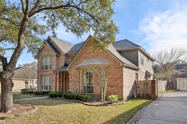 traditional home featuring a front yard, a gate, fence, and brick siding