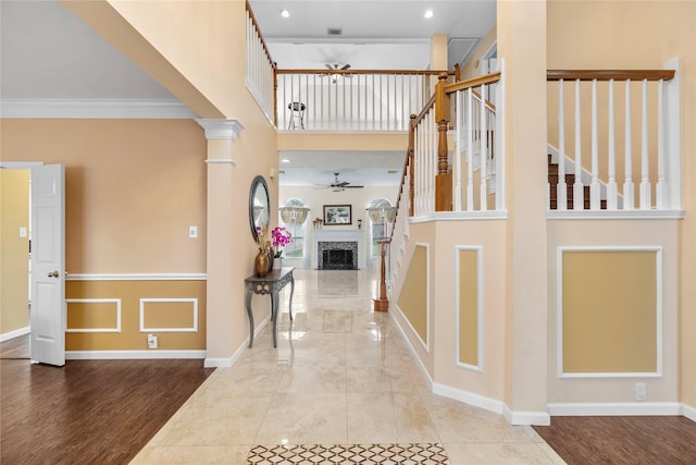 foyer entrance featuring a fireplace, stairway, a high ceiling, ceiling fan, and baseboards