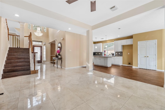 unfurnished living room featuring stairway, baseboards, visible vents, and arched walkways