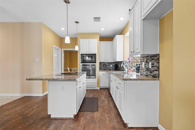 kitchen featuring a kitchen island, decorative light fixtures, light stone countertops, black appliances, and white cabinetry