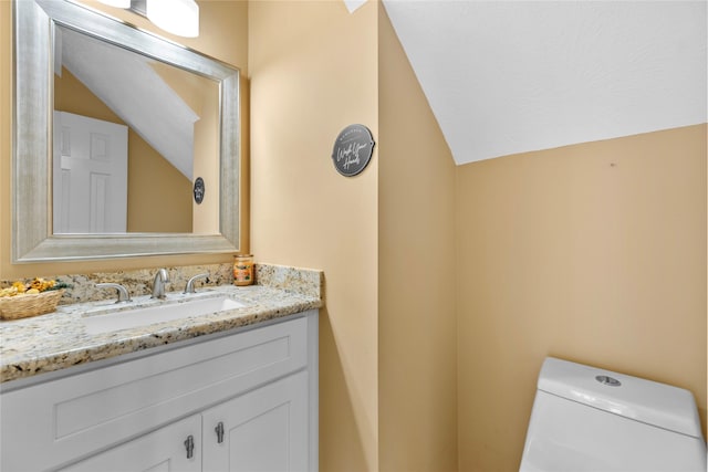 bathroom with toilet, vaulted ceiling, and vanity