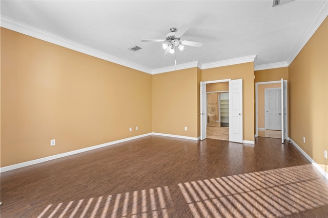 empty room with dark wood finished floors, visible vents, ornamental molding, ceiling fan, and baseboards