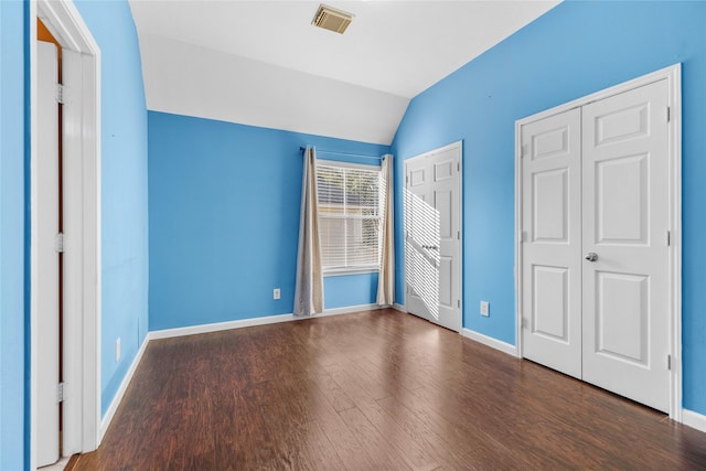 unfurnished bedroom with dark wood-type flooring, lofted ceiling, visible vents, and baseboards