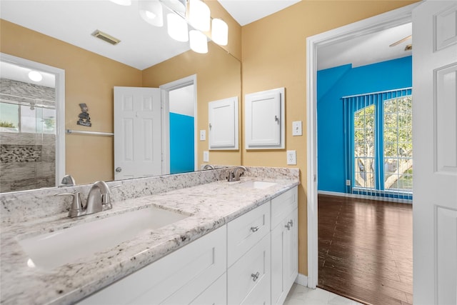 full bath featuring double vanity, a shower with door, visible vents, and a sink