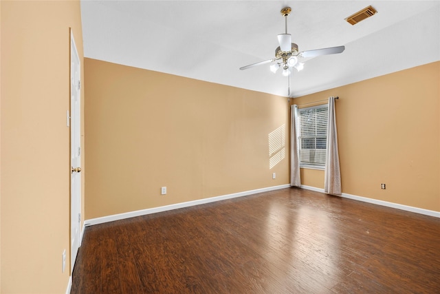 spare room with dark wood-type flooring, visible vents, ceiling fan, and baseboards