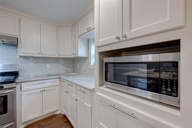 kitchen featuring stainless steel appliances, decorative backsplash, dark wood finished floors, and white cabinets