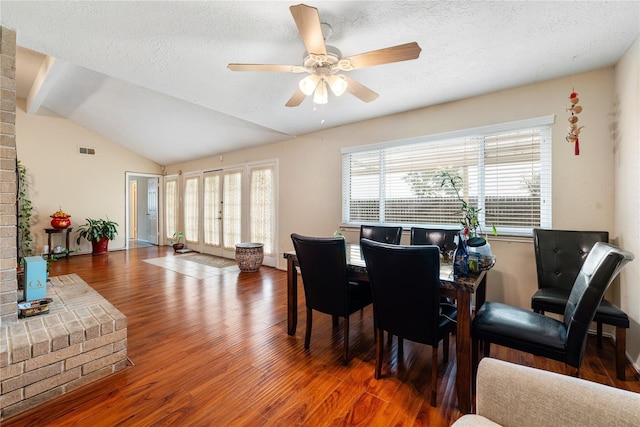 dining area with lofted ceiling, a textured ceiling, visible vents, and wood finished floors