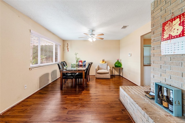 dining area featuring a ceiling fan, a textured ceiling, visible vents, and wood finished floors