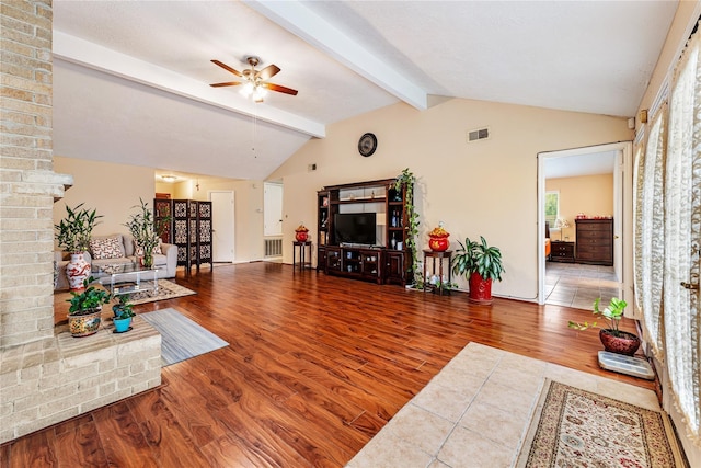 living room featuring vaulted ceiling with beams, wood finished floors, visible vents, and a ceiling fan