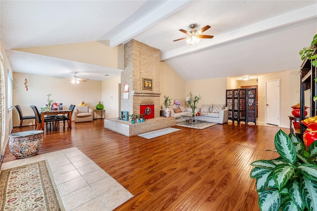 living area with a ceiling fan, a fireplace, lofted ceiling with beams, and wood finished floors