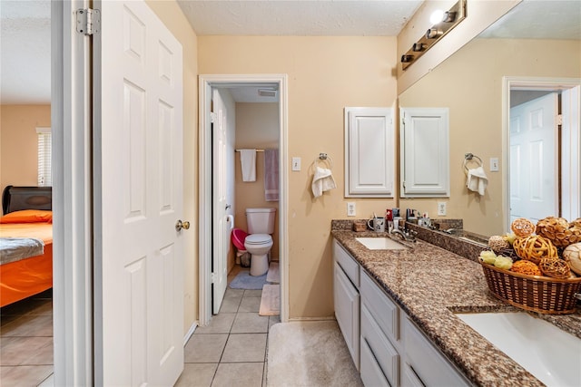 full bathroom featuring double vanity, toilet, a sink, and tile patterned floors