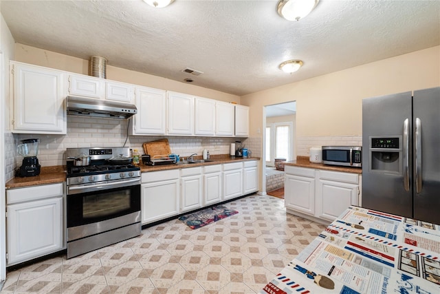 kitchen with light floors, stainless steel appliances, visible vents, white cabinetry, and under cabinet range hood