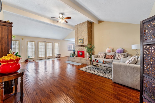 living room featuring lofted ceiling with beams, a textured ceiling, a fireplace, and wood finished floors