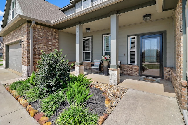 doorway to property featuring a garage, roof with shingles, a porch, and brick siding