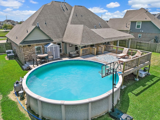 view of pool with a fenced in pool, an outbuilding, a lawn, a storage shed, and a wooden deck