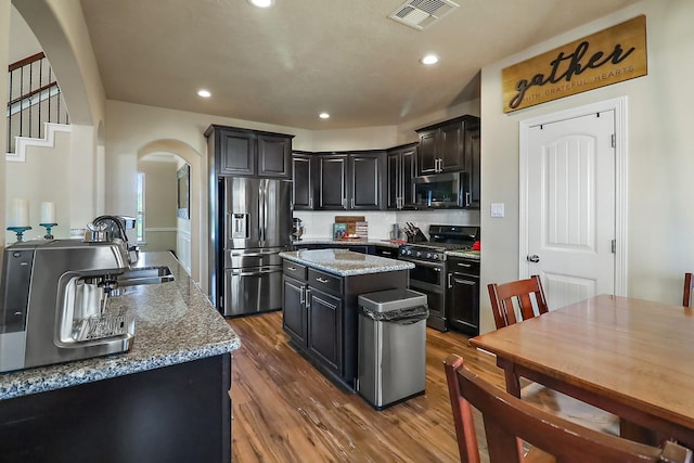 kitchen featuring visible vents, a kitchen island, appliances with stainless steel finishes, and light stone counters