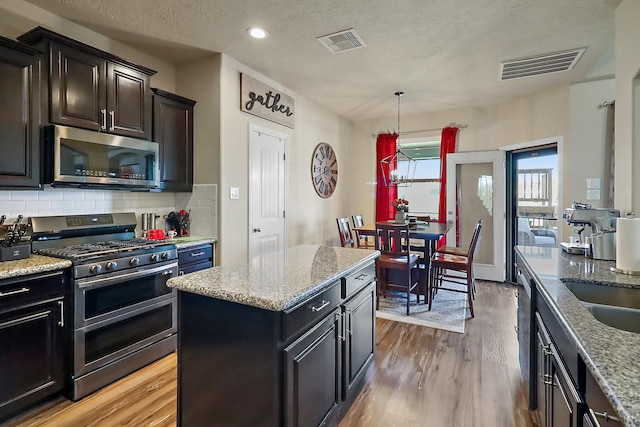 kitchen featuring visible vents, appliances with stainless steel finishes, tasteful backsplash, and a center island