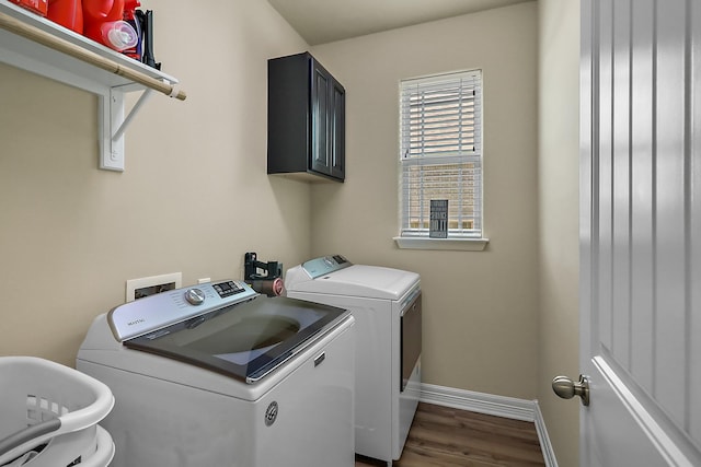 laundry area featuring dark wood finished floors, washing machine and dryer, cabinet space, and baseboards