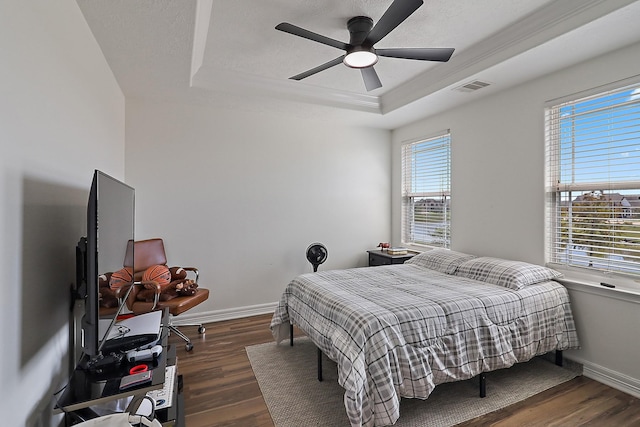 bedroom featuring a textured ceiling, dark wood-type flooring, visible vents, baseboards, and a raised ceiling