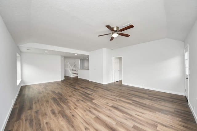 unfurnished living room featuring baseboards, lofted ceiling, ceiling fan, stairway, and dark wood-type flooring