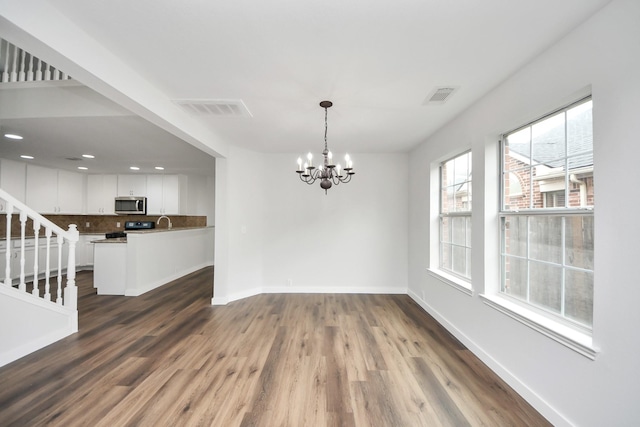 unfurnished dining area with dark wood-style floors, visible vents, stairway, and baseboards