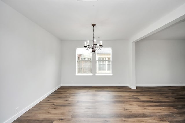 unfurnished dining area with an inviting chandelier, baseboards, and dark wood finished floors