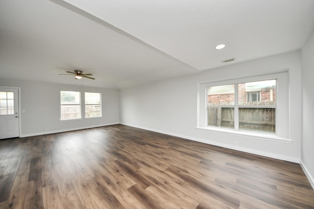 unfurnished room featuring visible vents, wood finished floors, a ceiling fan, and baseboards