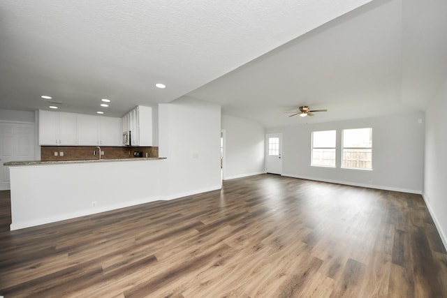 unfurnished living room with baseboards, ceiling fan, wood finished floors, a sink, and recessed lighting