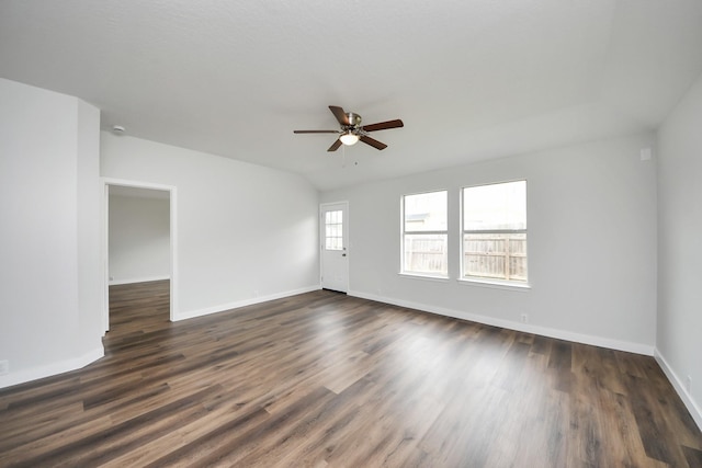 empty room with dark wood finished floors, a ceiling fan, and baseboards