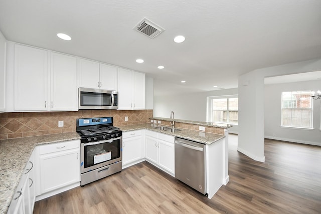 kitchen with a peninsula, visible vents, appliances with stainless steel finishes, and white cabinets