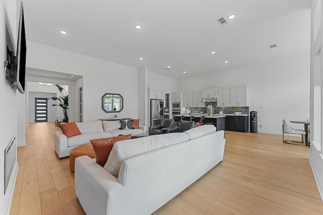 living room featuring light wood-style flooring, visible vents, and recessed lighting