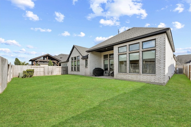 back of property with a yard, a gazebo, brick siding, and a fenced backyard