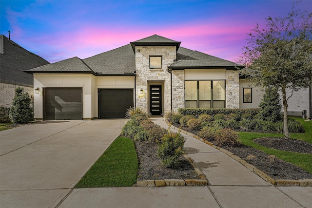 prairie-style home with a garage, stone siding, driveway, and a shingled roof