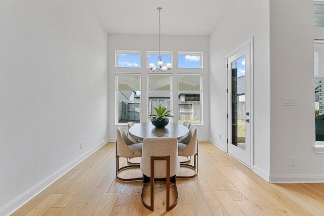 dining room with light wood-style floors, baseboards, and an inviting chandelier