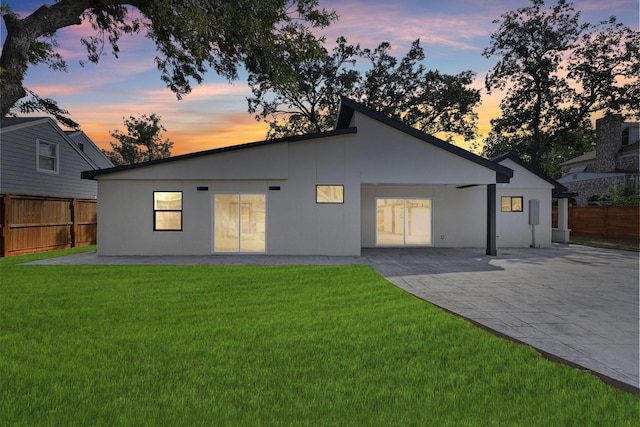 rear view of house featuring stucco siding, a fenced backyard, a yard, and a patio