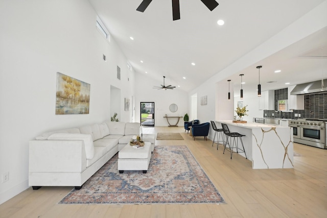 living area featuring visible vents, high vaulted ceiling, a ceiling fan, and light wood-style floors