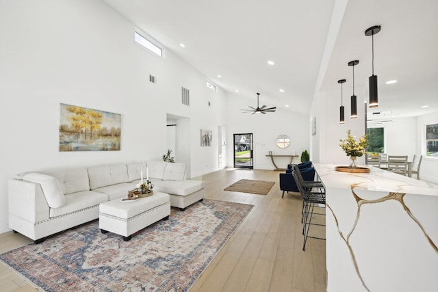 living area with recessed lighting, visible vents, a high ceiling, light wood-style floors, and ceiling fan