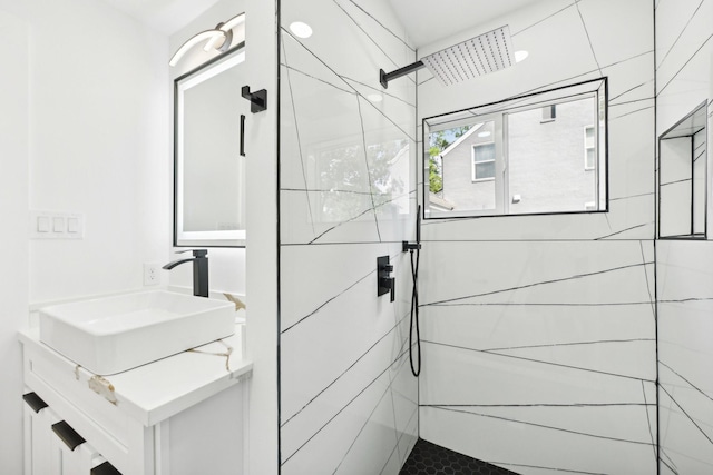 full bathroom with tiled shower and vanity