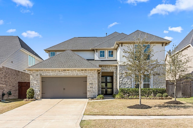 view of front of house with driveway, stone siding, roof with shingles, an attached garage, and french doors