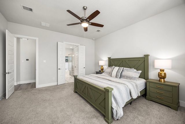 bedroom featuring baseboards, visible vents, ensuite bathroom, and light colored carpet