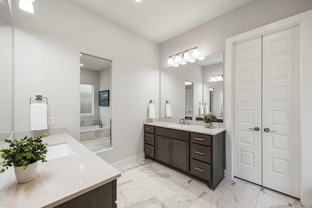 bathroom featuring a garden tub, two vanities, a sink, baseboards, and marble finish floor