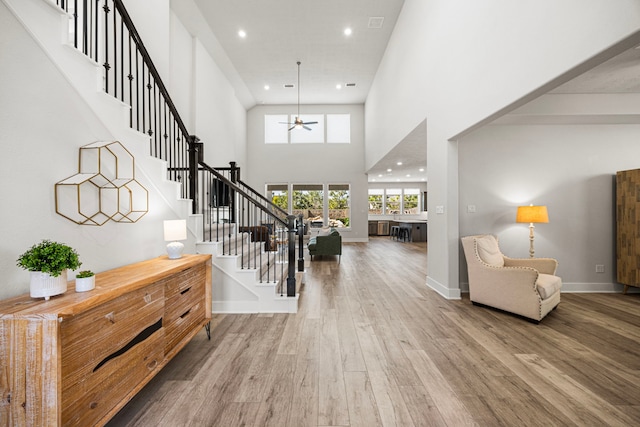 foyer entrance with recessed lighting, wood finished floors, a towering ceiling, baseboards, and stairway