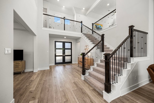 foyer entrance with french doors, stairway, wood finished floors, and baseboards