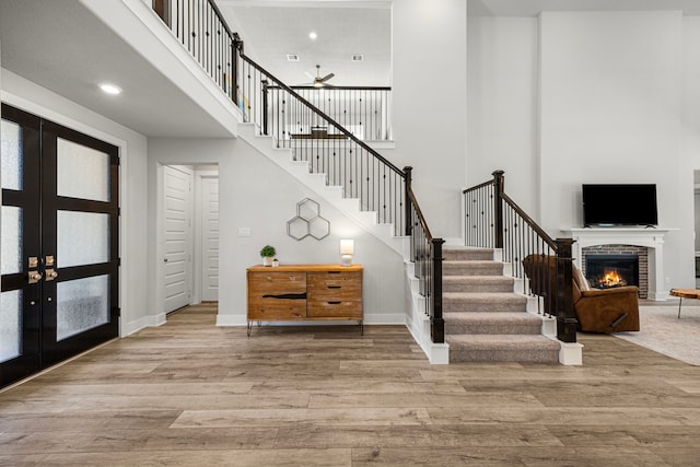 foyer featuring french doors, stairway, a fireplace, and light wood-style flooring